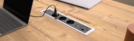 Différentes prises (usb, rj45, courant) sur un bureau avec des ordinateurs