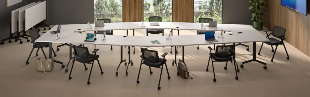 Salle de réunion avec une grande table de réunion avec des ordinateurs et des chaises sur roulettes